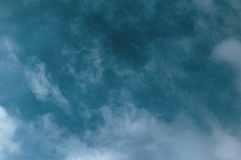 a plane flying through a cloudy blue sky