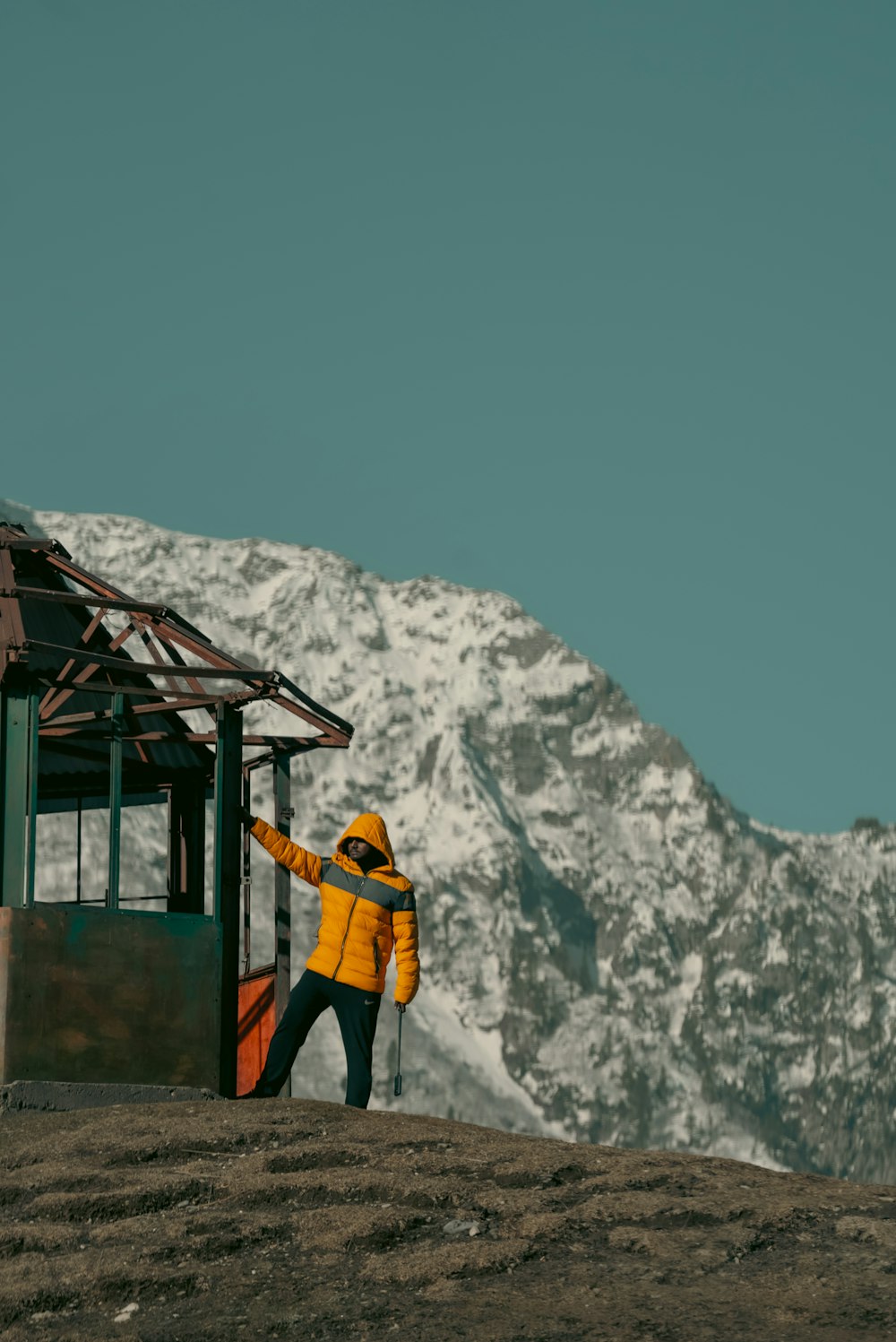 a man in a yellow jacket standing in front of a mountain