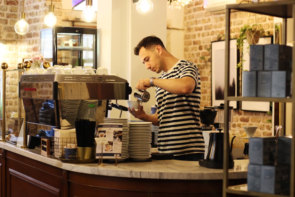 a man standing at a counter making a cup of coffee