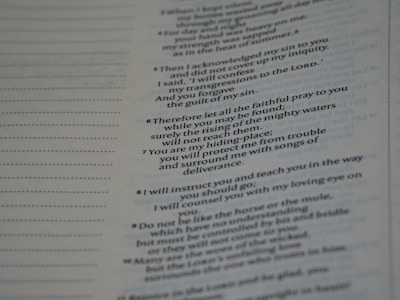 A close-up view of a book or document showing a section of text printed in a serif font. The text contains numbered lines, potentially verses or key points, and is formatted in a column layout. The background is a light color, typical of paper. The text on the left shows dotted lines, possibly for notes or annotations.
