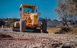 Heavy machinery compacting road material on a rural road construction site.
