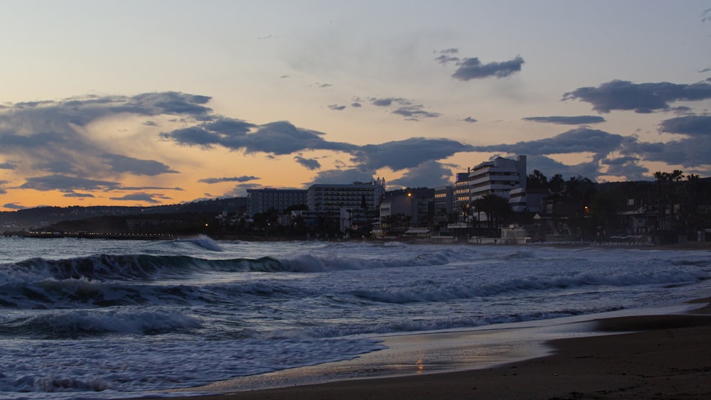 a sunset view of a beach with a city in the background