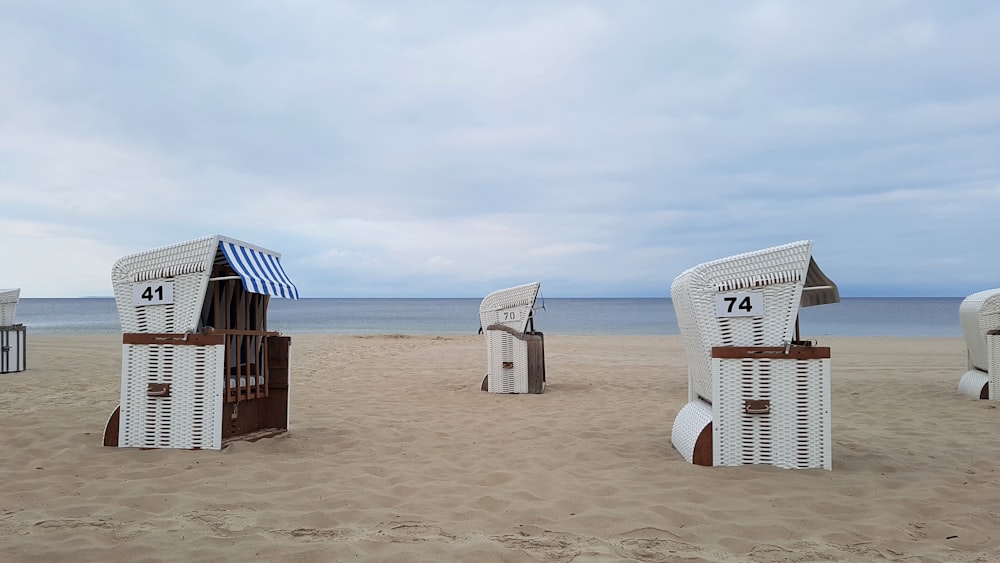 a group of white chairs sitting on top of a sandy beach