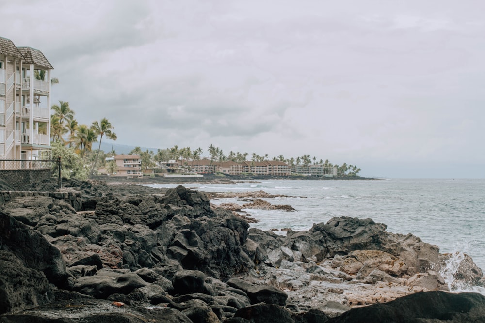 a white building sitting on top of a rocky beach