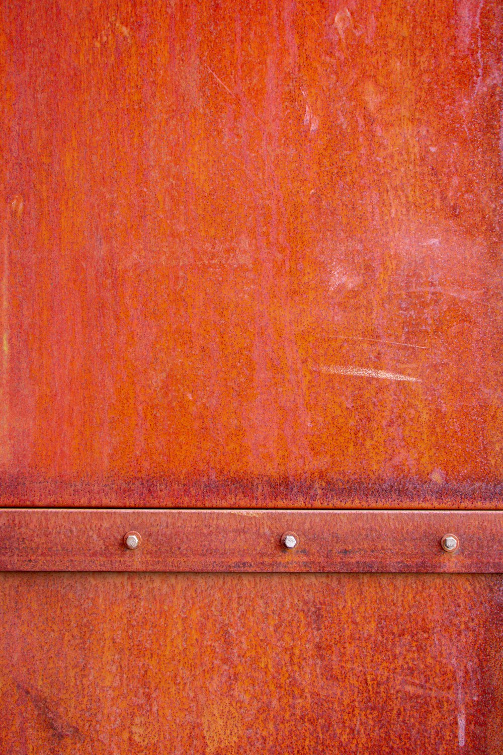 a close up of a red metal surface with rivets