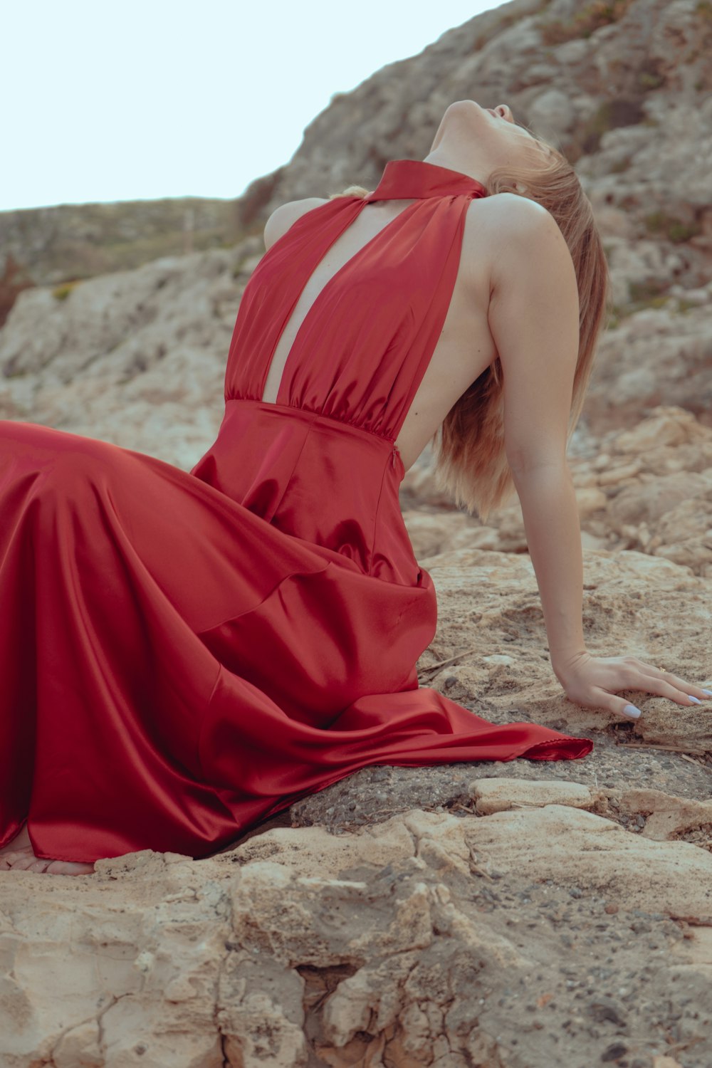 a woman in a red dress sitting on a rock