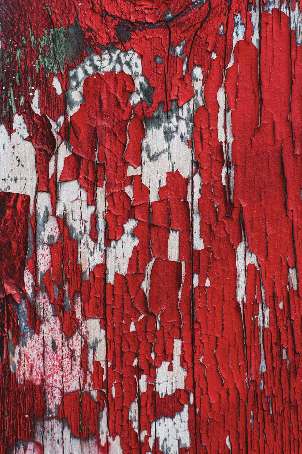 a close up of a red and white wall with peeling paint