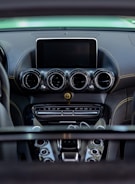 A detailed view of a car's dashboard featuring multiple air vents, a central display screen, and various control buttons. The dashboard has a sleek, modern design with a combination of dark and metallic finishes.
