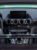 A detailed view of a car's dashboard featuring multiple air vents, a central display screen, and various control buttons. The dashboard has a sleek, modern design with a combination of dark and metallic finishes.