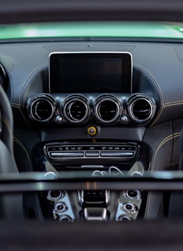 A detailed view of a car's dashboard featuring multiple air vents, a central display screen, and various control buttons. The dashboard has a sleek, modern design with a combination of dark and metallic finishes.