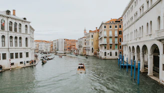 a boat traveling down a river next to tall buildings