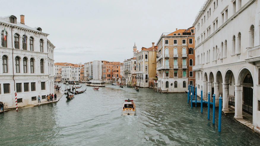a boat traveling down a river next to tall buildings