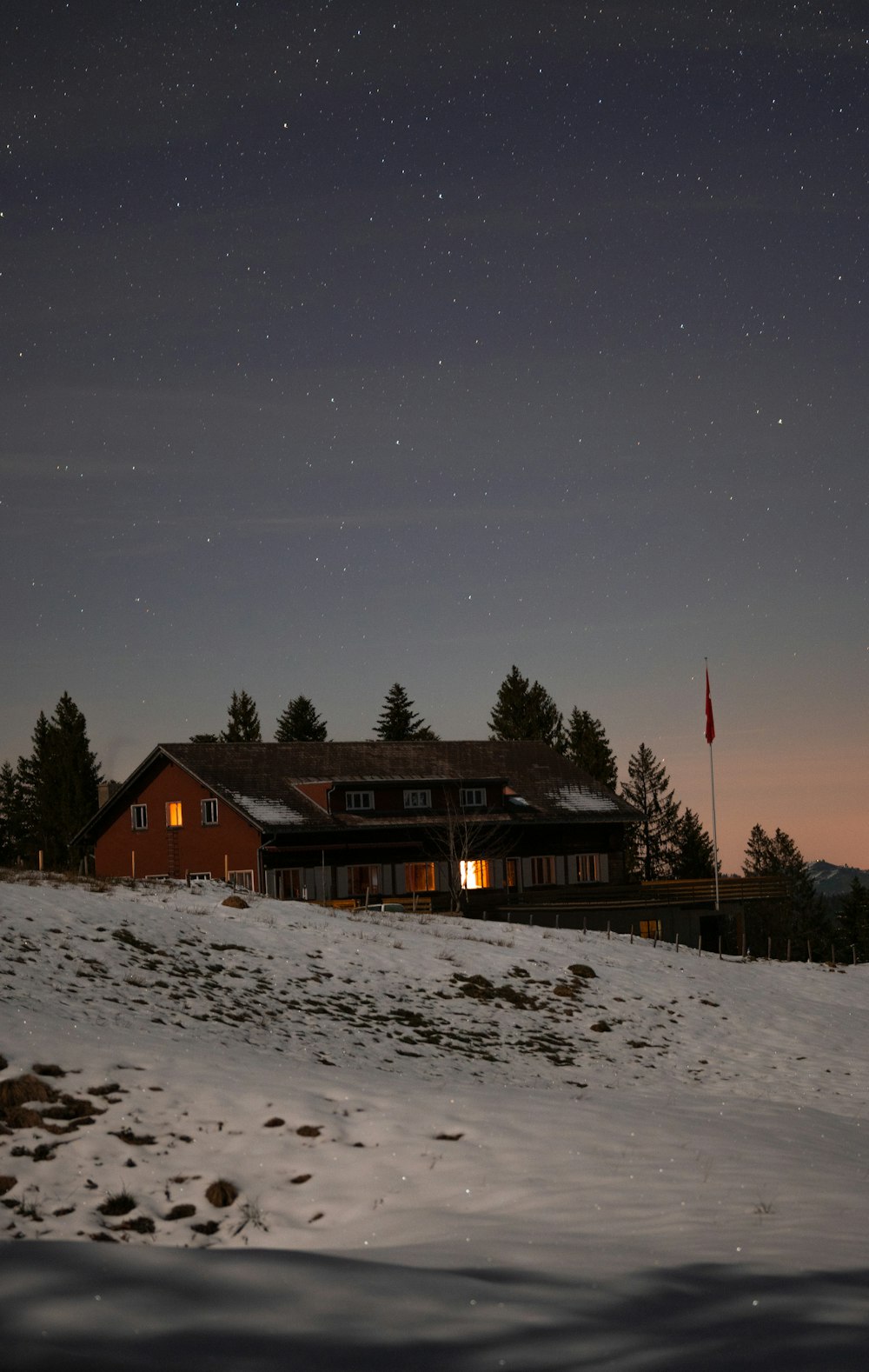 a house is lit up at night in the snow