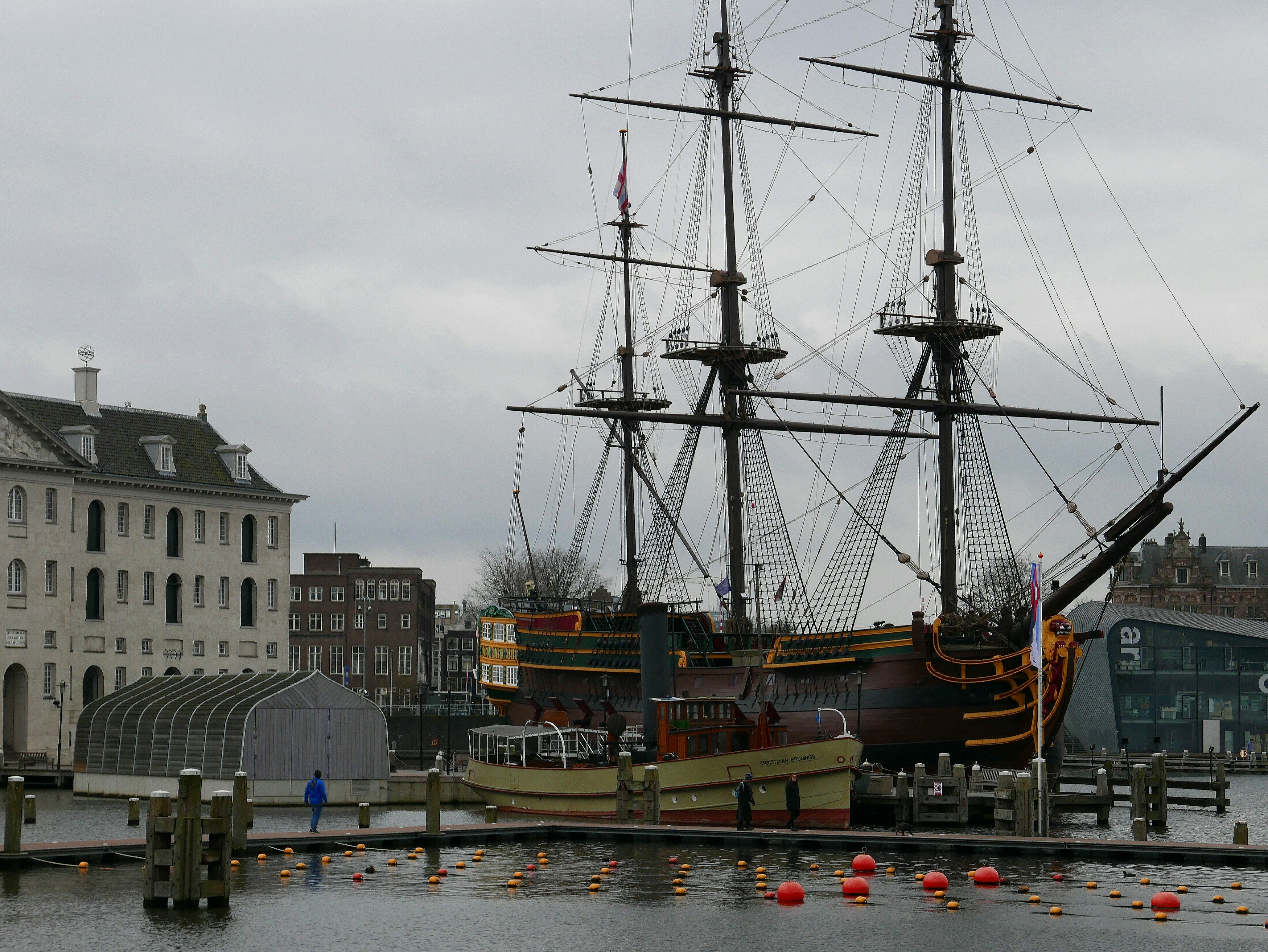 A 17th century wooden sailing ship (replica) De Amsterdam is located near the historical Maritime store house. The building was built in 17th century, but the ship is a truly replica of an old original one. Picture of Amsterdam old buildings - Dutch photography in free photo by Fons Heijnsbroek, Netherlands // Foto van replica van een V.O.C. schip met 3 masten: De Amsterdam, naast historische gebouw van het Scheepvaartmuseum, vroeger marine pakhuis - gratis downloaden. Foto, Fons Heijnsbroek - fotografie van oude schepen en gebouwen in Nederland, hoge resolutie en rechtenvrije afbeelding, CCO