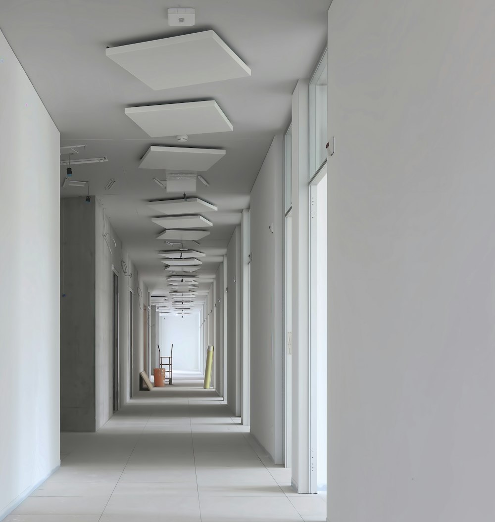 um longo corredor com paredes brancas e luzes de teto