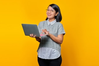 a woman holding a laptop computer on a yellow background