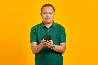 a man in a green shirt looking at a cell phone