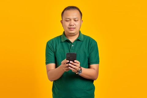 a man in a green shirt looking at a cell phone
