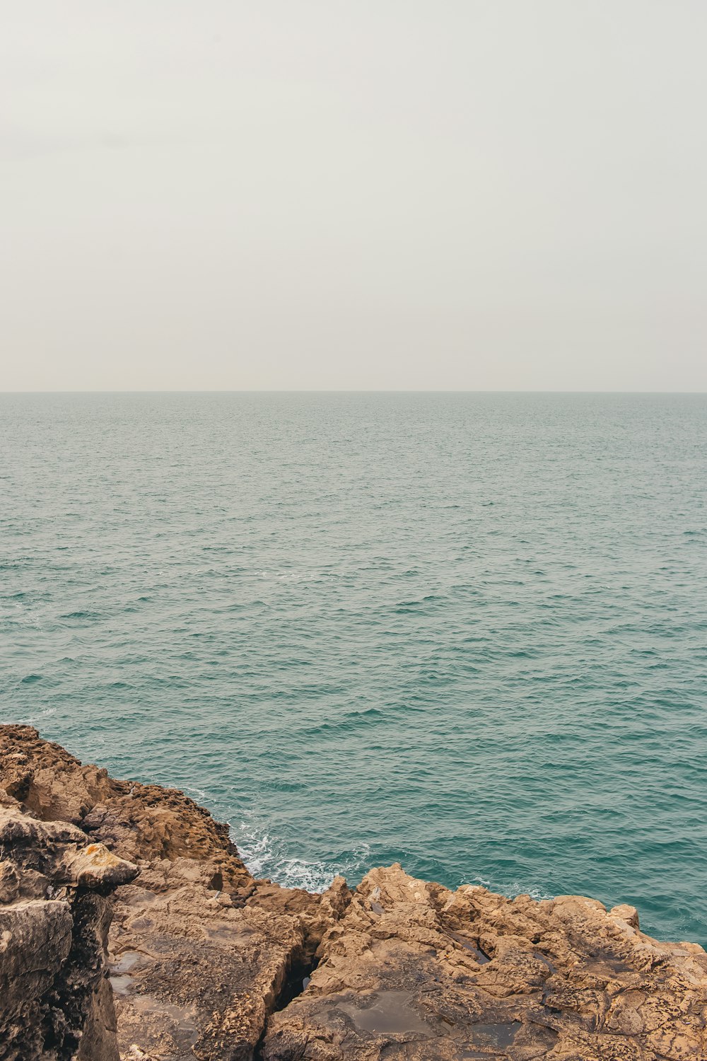 a man sitting on a rock near the ocean