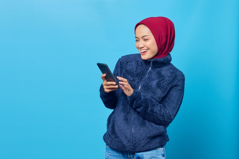 a woman in a blue sweater is looking at her cell phone