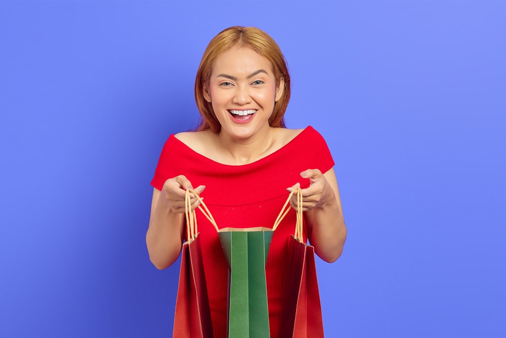 a woman in a red dress holding shopping bags