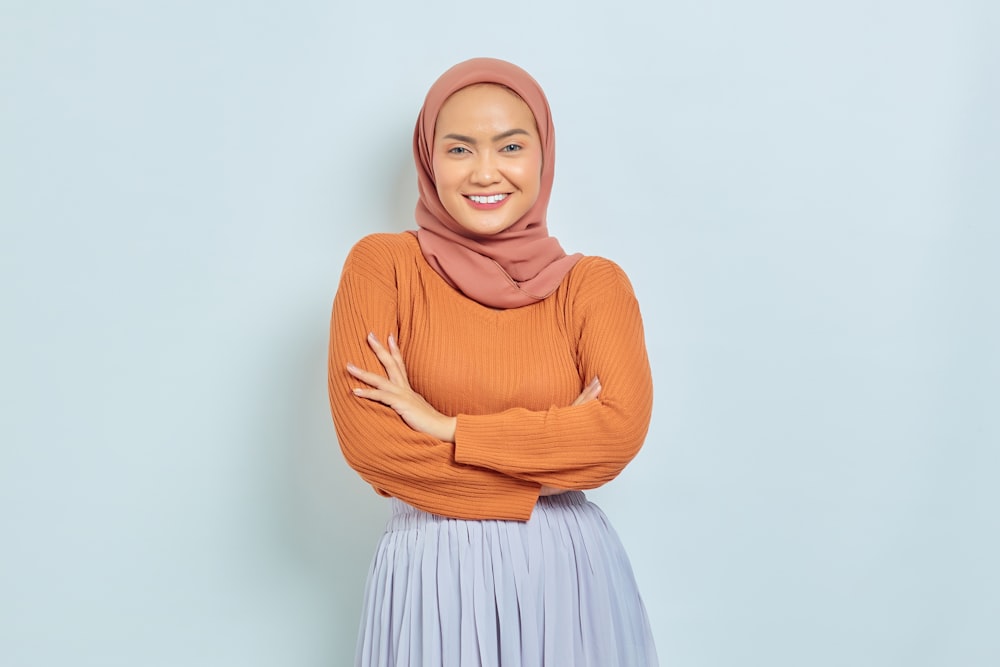 a woman wearing a hijab standing with her arms crossed