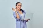 a woman in glasses is holding a laptop