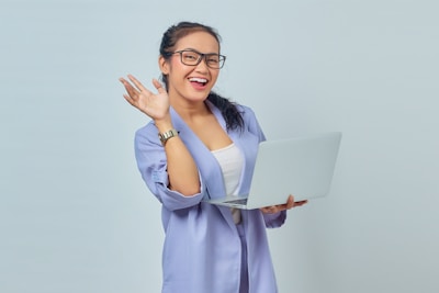 a woman in glasses is holding a laptop