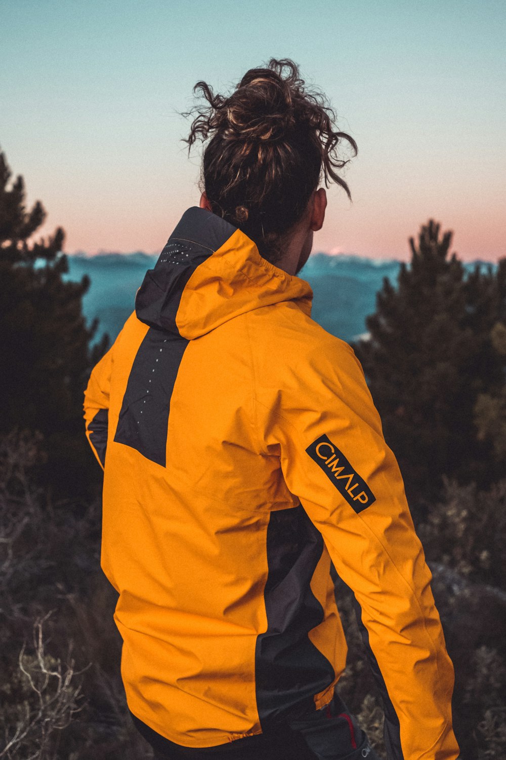 a man in a yellow jacket looking out over the ocean