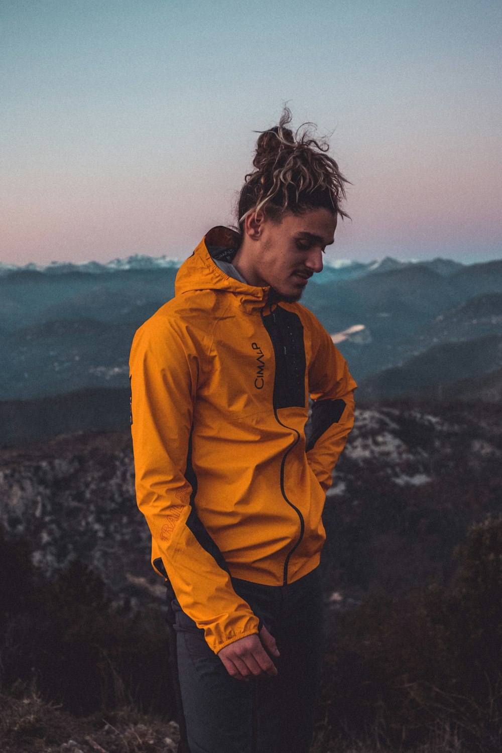a man standing on top of a mountain in a yellow jacket