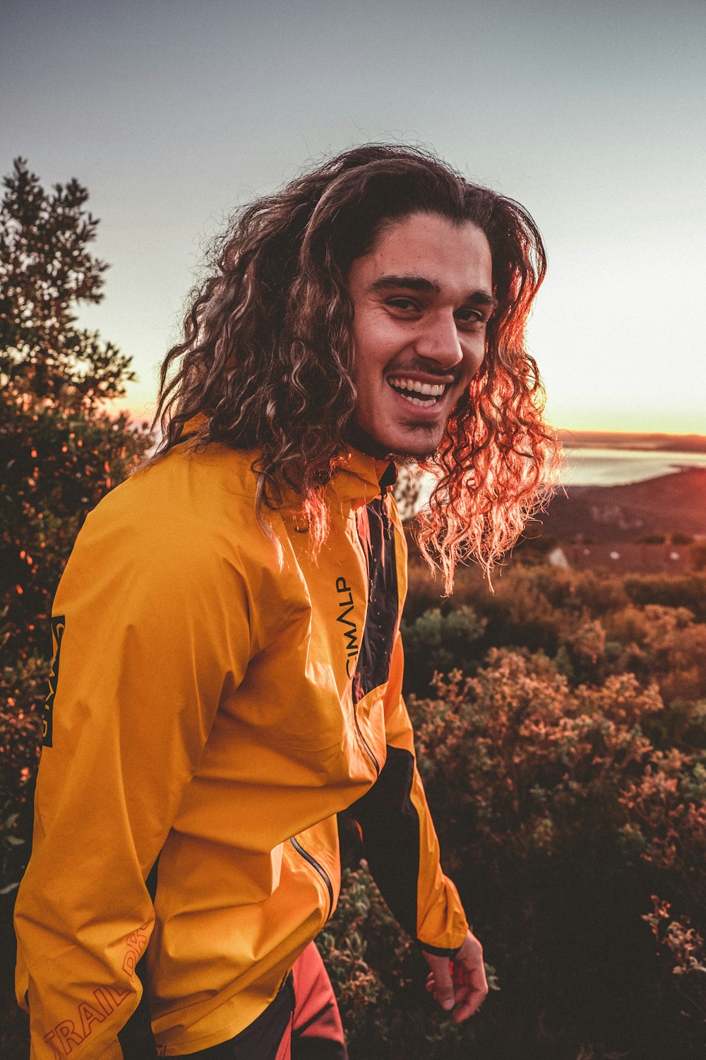 a man with long hair is smiling at the camera