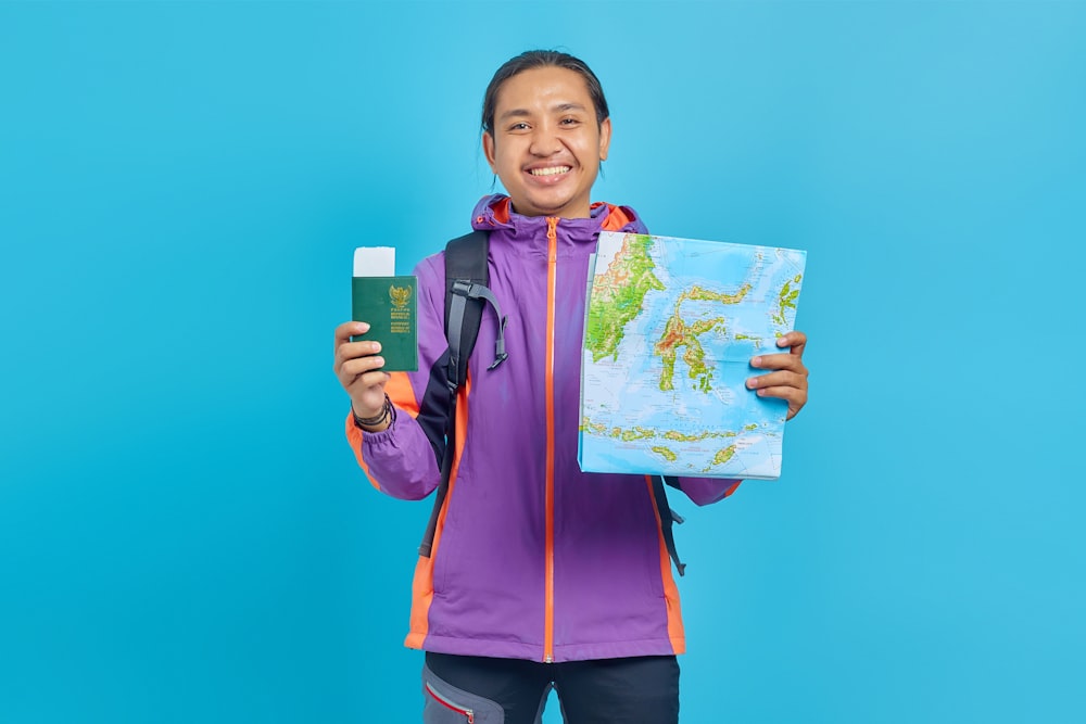a man in a purple jacket holding a map and a passport