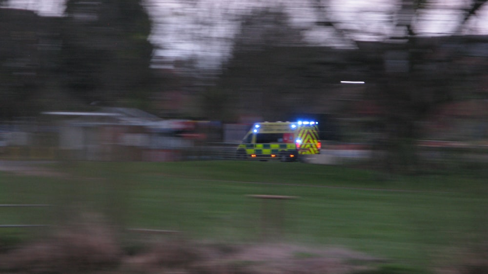 a police car driving down a street next to a lush green field