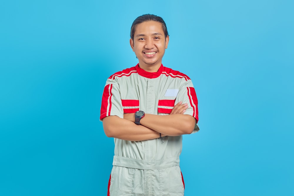 a man with his arms crossed standing in front of a blue background