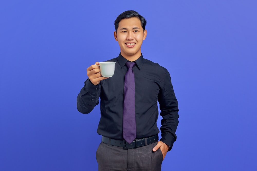 a man in a black shirt and tie holding a cup of coffee
