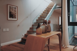 Маса с вази до стълбище, боядисано в кремав светъл тон, подчертаваща спокойната зона.