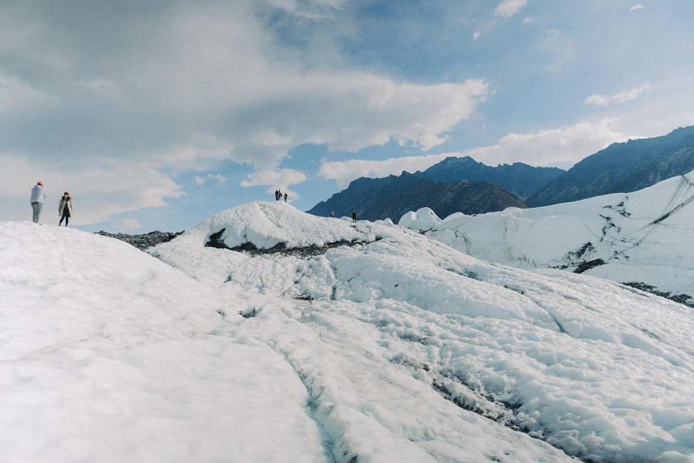 a couple of people standing on top of a snow covered slope