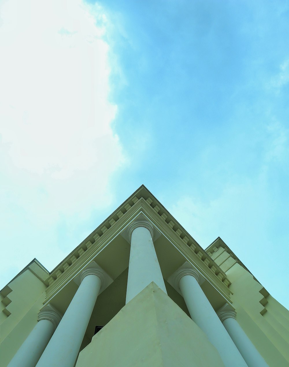 a tall white building with columns and a sky background