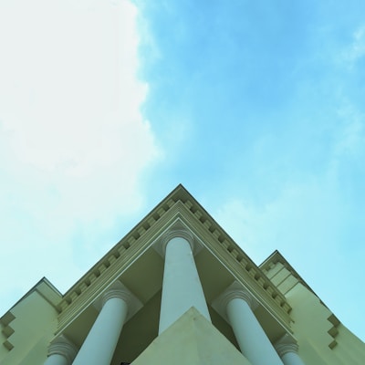 a tall white building with columns and a sky background