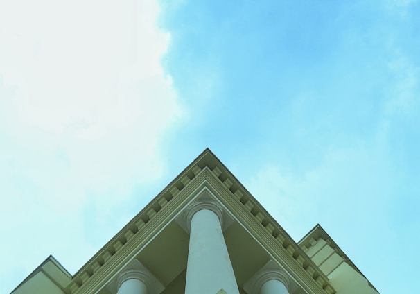 a tall white building with columns and a sky background