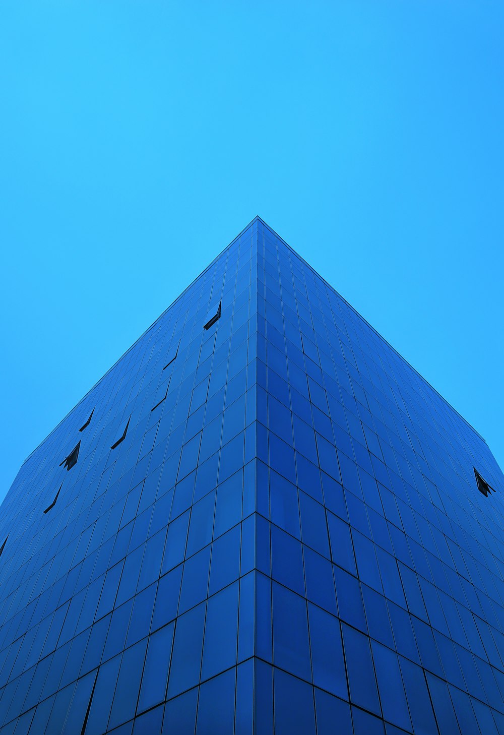 a very tall blue building with a sky background