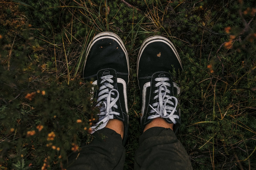 a person wearing black and white shoes standing in the grass