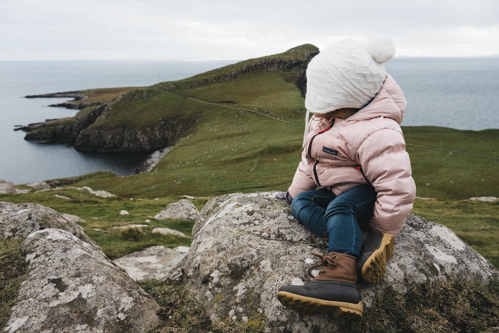 una bambina seduta sulla cima di una grande roccia