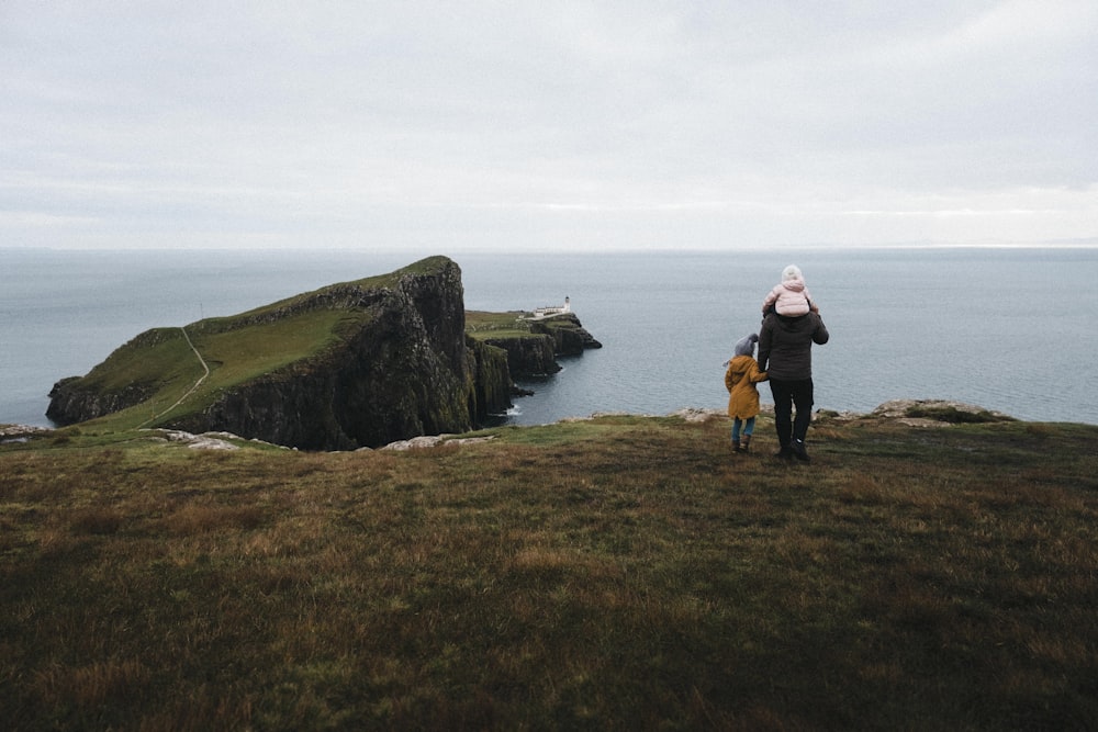 a person standing on top of a hill next to a body of water