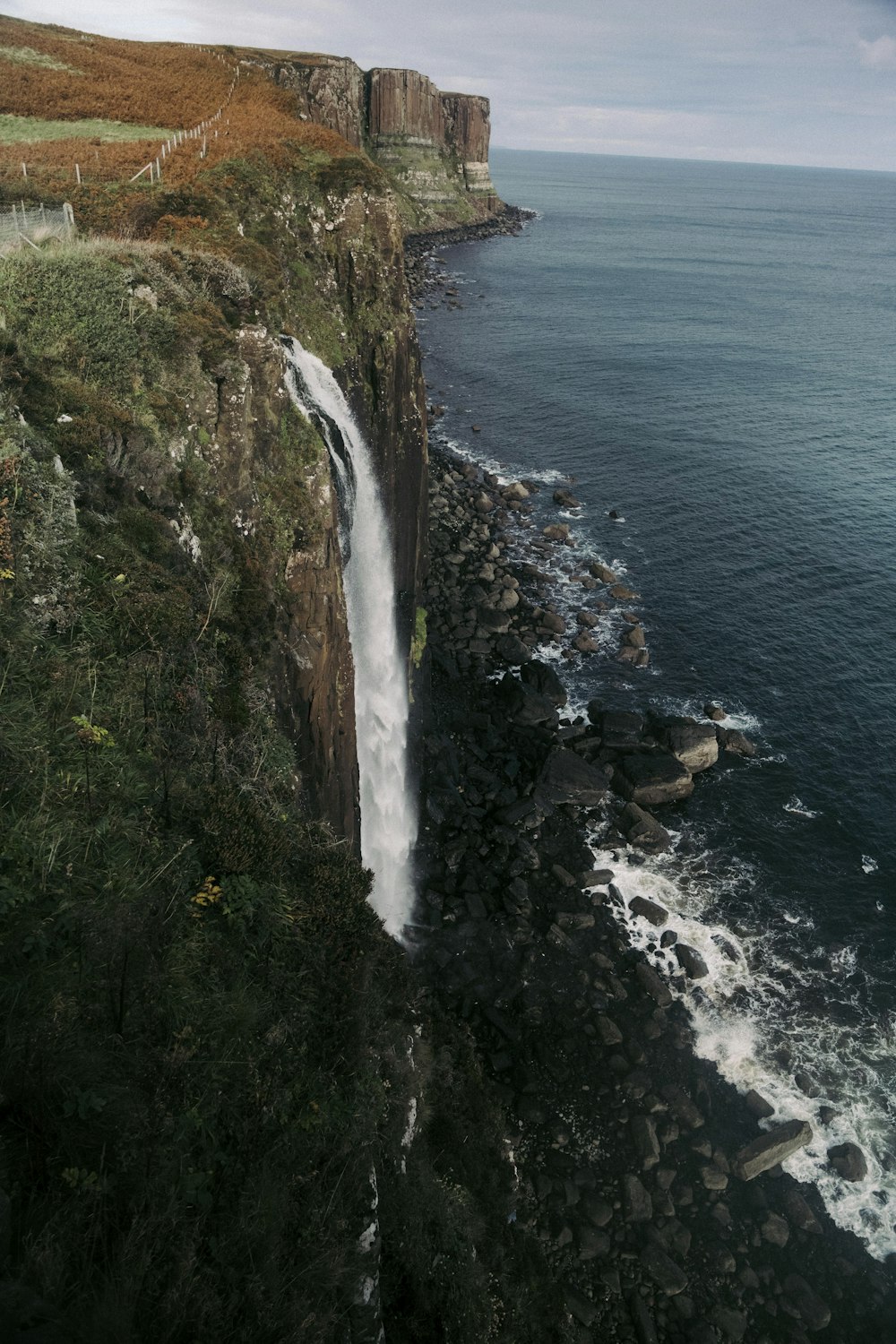 a large waterfall on the side of a cliff near the ocean