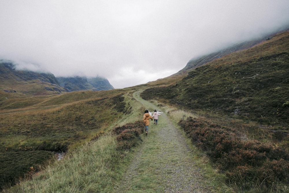 a couple of people walking down a dirt road