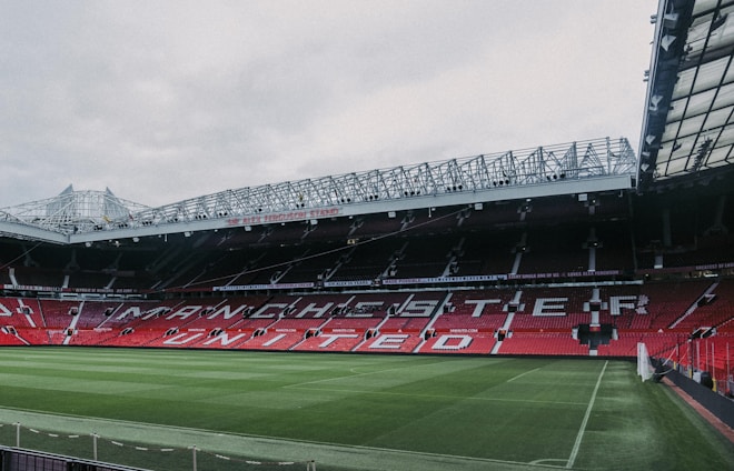 a stadium with a green field and red seats