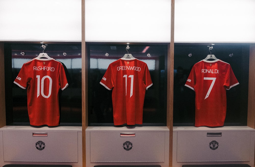 a display case with three red soccer jerseys