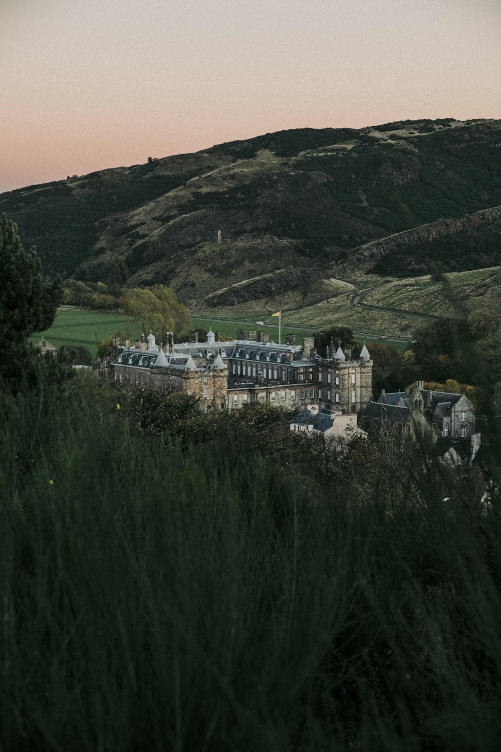 Un grand bâtiment assis au sommet d’une colline verdoyante