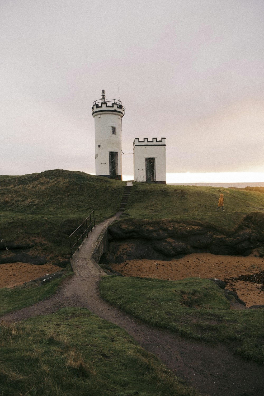 a lighthouse on top of a grassy hill